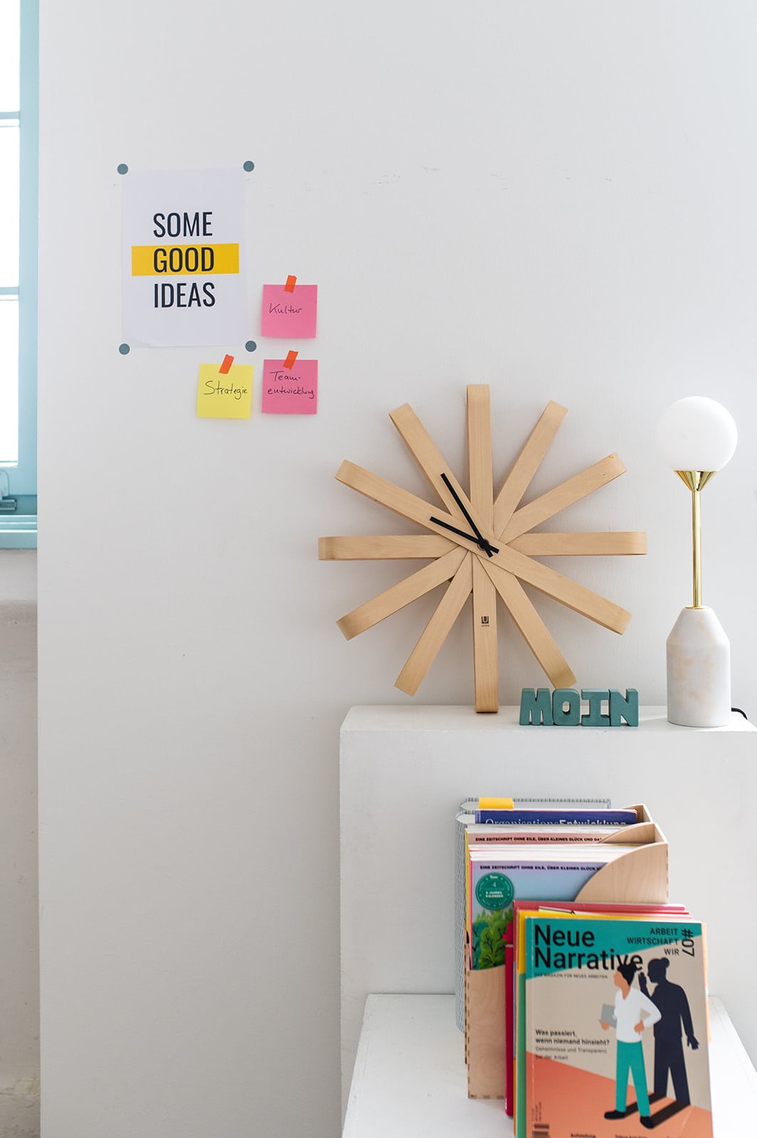 Modernes Wandbild mit Holzuhruhr, Notizzetteln und Dekorationsobjekten.