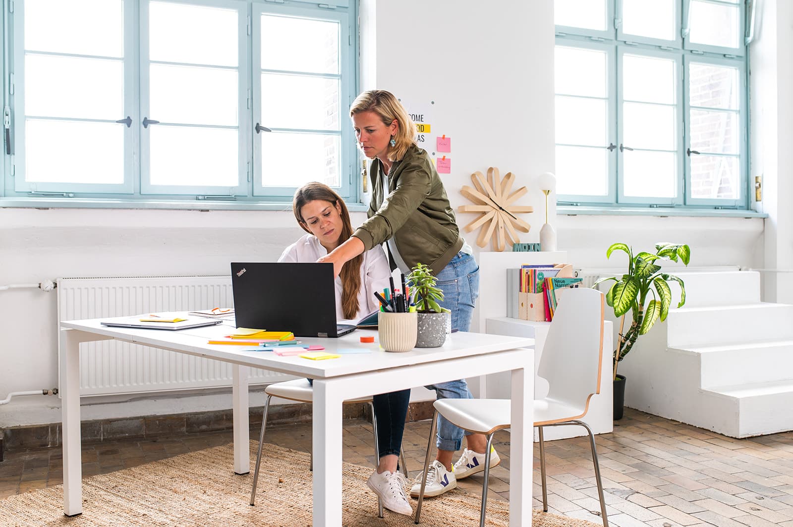 Zwei Frauen arbeiten gemeinsam an einem modernen Schreibtisch im hellen Büro.