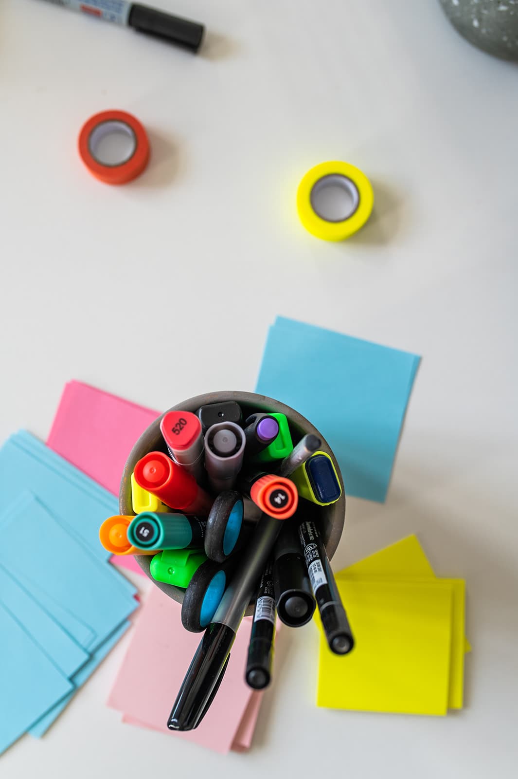 Buntes Marker-Set mit Filzstiften, Post-its und Klebeband auf weißem Tisch.