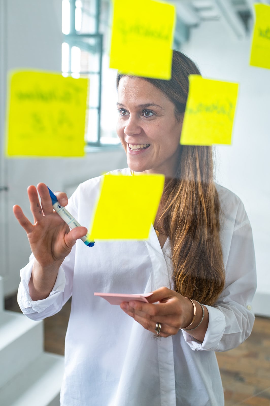 Frau plant kreative Ideen mit Post-its und Tablet in modernem Büro.