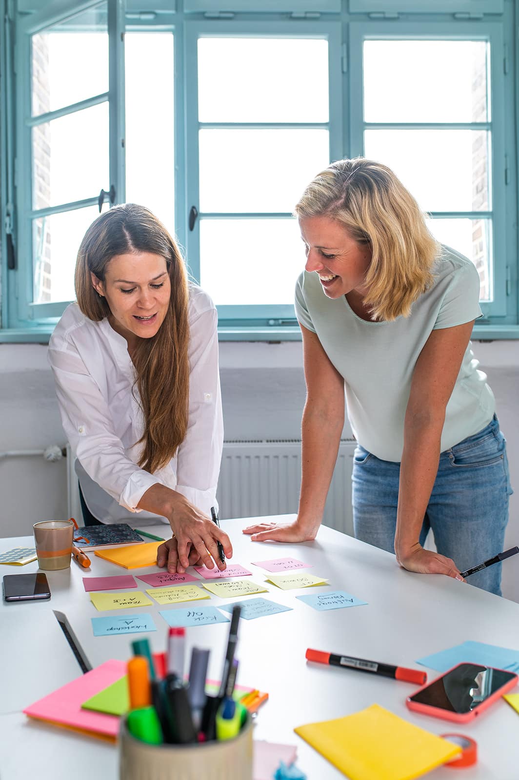 Zwei Frauen diskutieren kreative Ideen bei einem Team-Meeting im Büro.