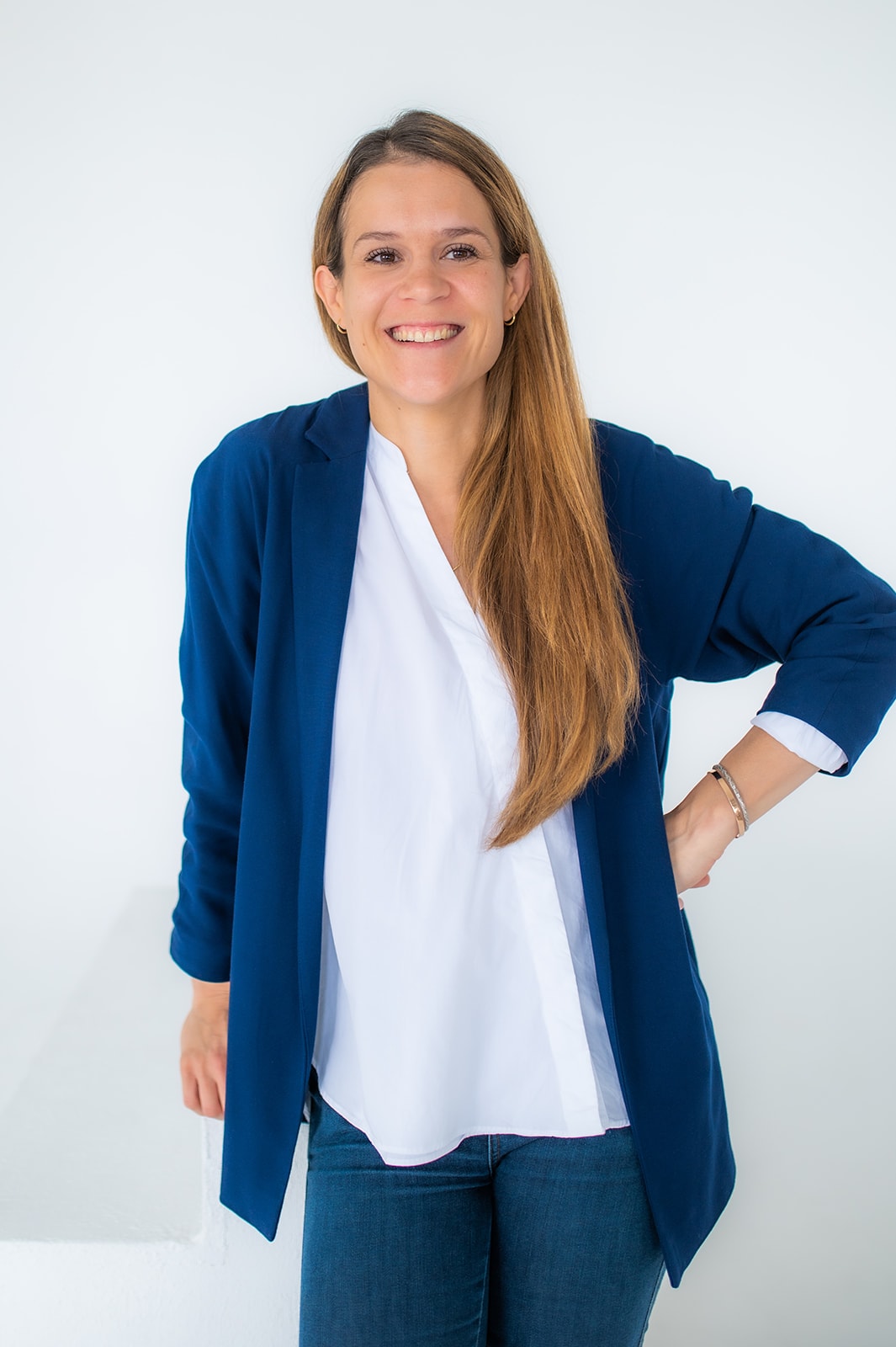 Fröhliche Geschäftsfrau in blauer Jacke vor weißem Hintergrund.