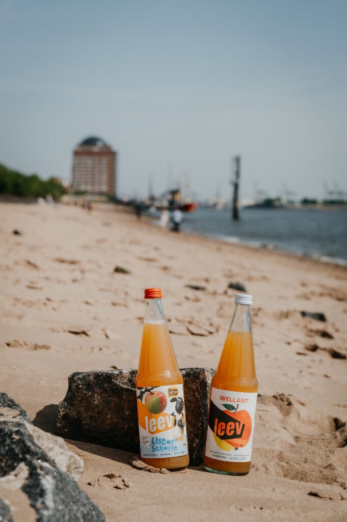 two bottles of juice on a beach