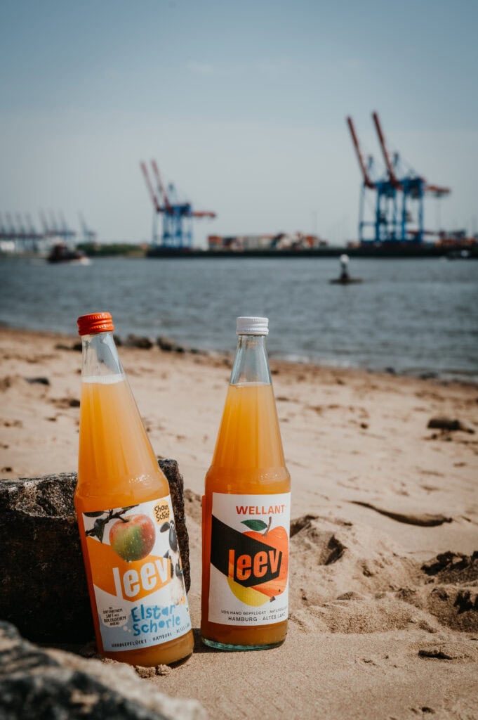 two bottles of juice on a beach