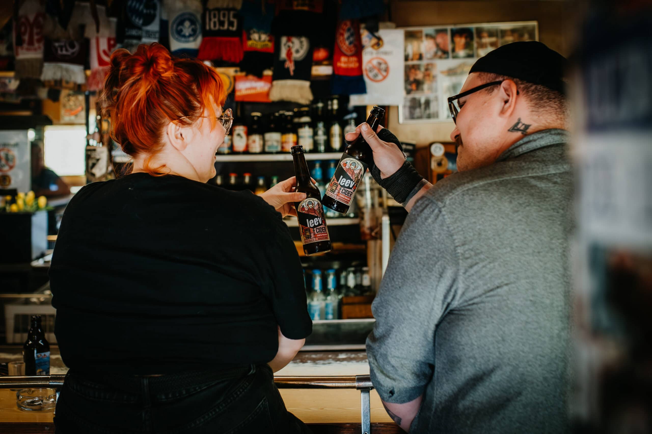 a man and woman holding bottles of cidre