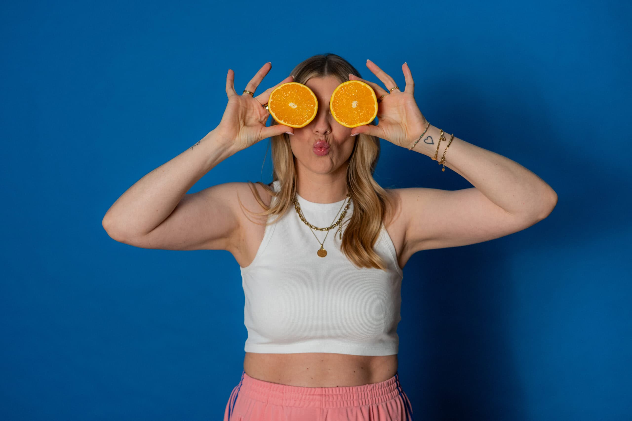 Frau hält Orangenhälften vor die Augen, spielt mit Obst, lustiges Foto.