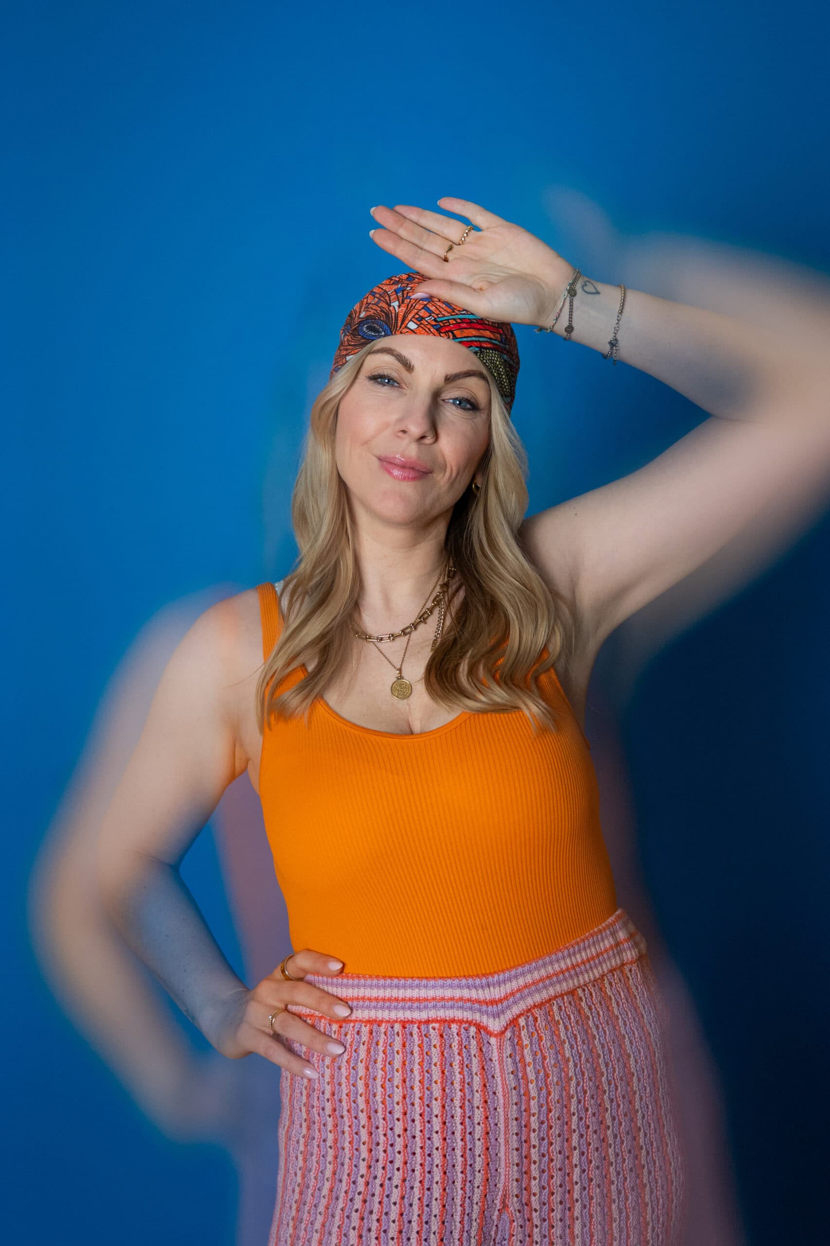 Junge Frau mit Sonnenbrille, buntem Kopftuch und sommerlicher Kleidung.