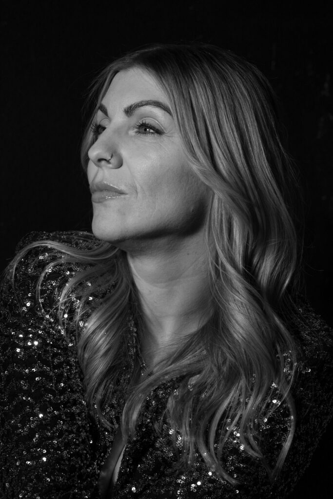 Elegante Frau mit langem Haar, stilvoll und selbstbewusst, in Schwarz-Weiß aufgenommen.