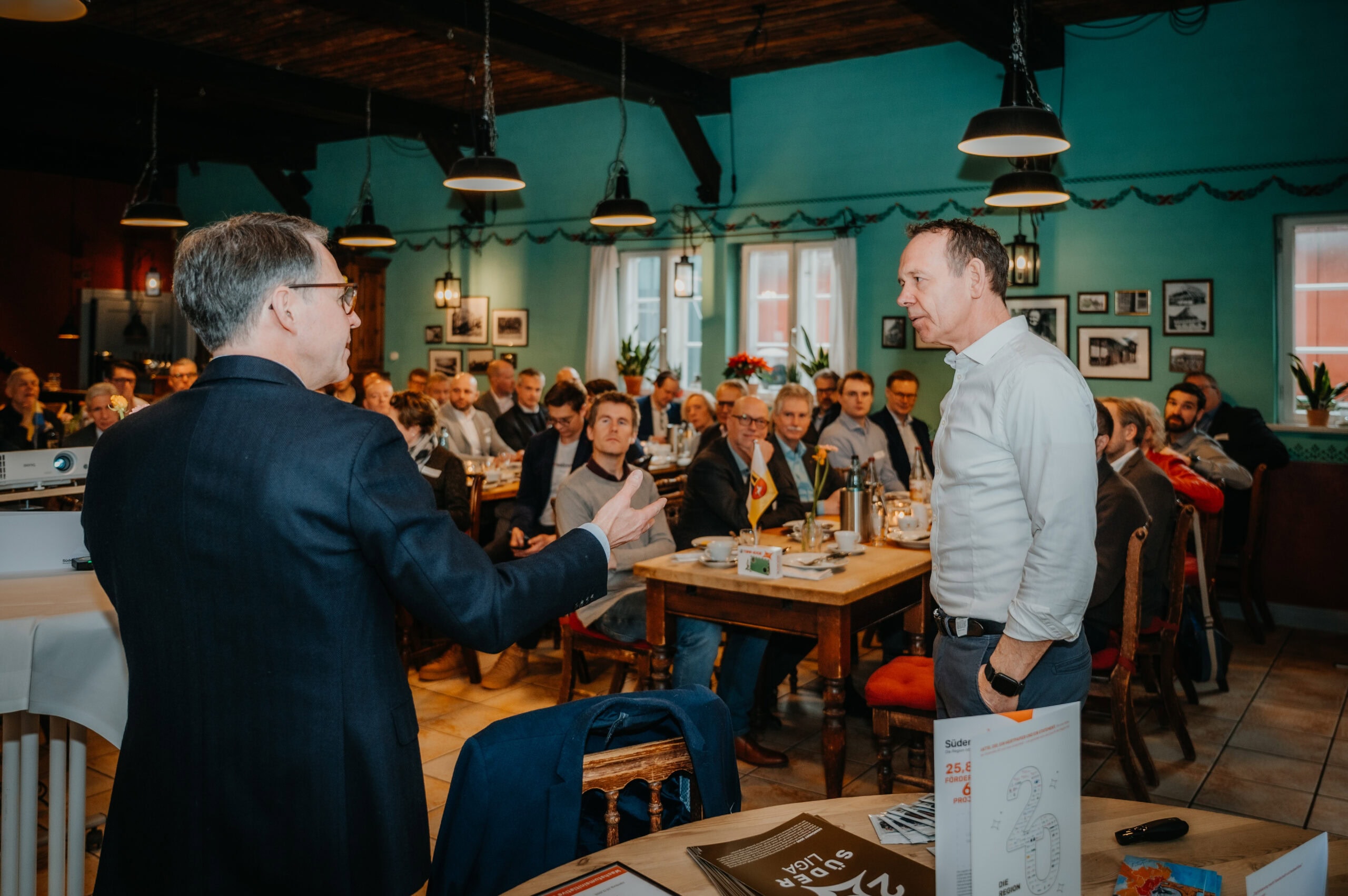 Geschäftspräsentation mit Redner vor Publikum in einem gemütlichen Restaurant.