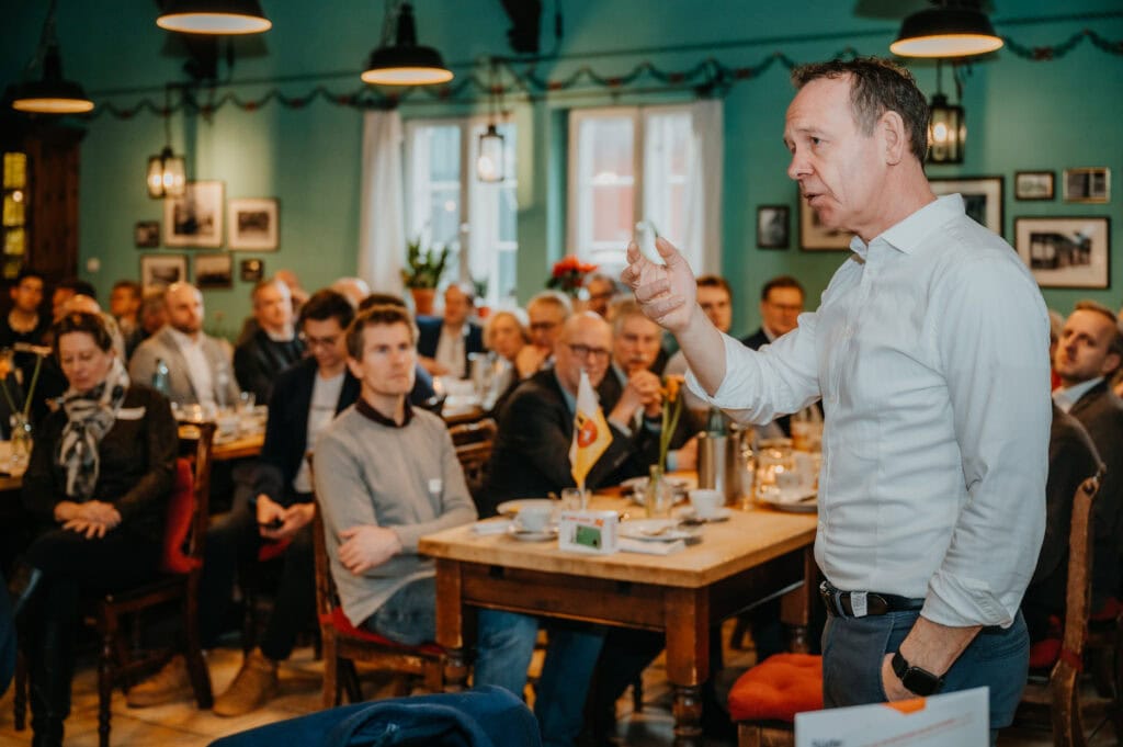 Mann hält Präsentation vor Publikum in gemütlichem Restaurant.