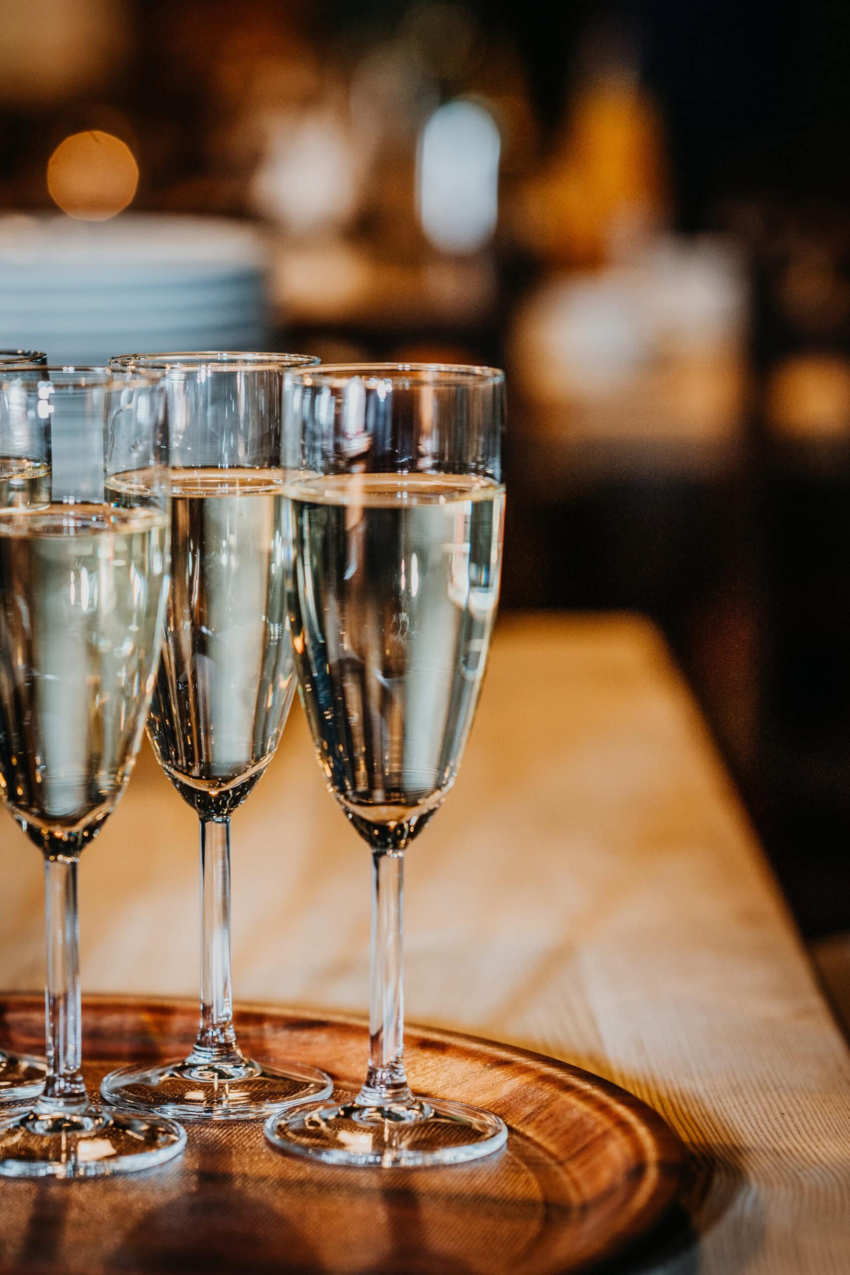 Mehrere Sektgläser mit Champagner auf Holzplatte, festliche Stimmung.