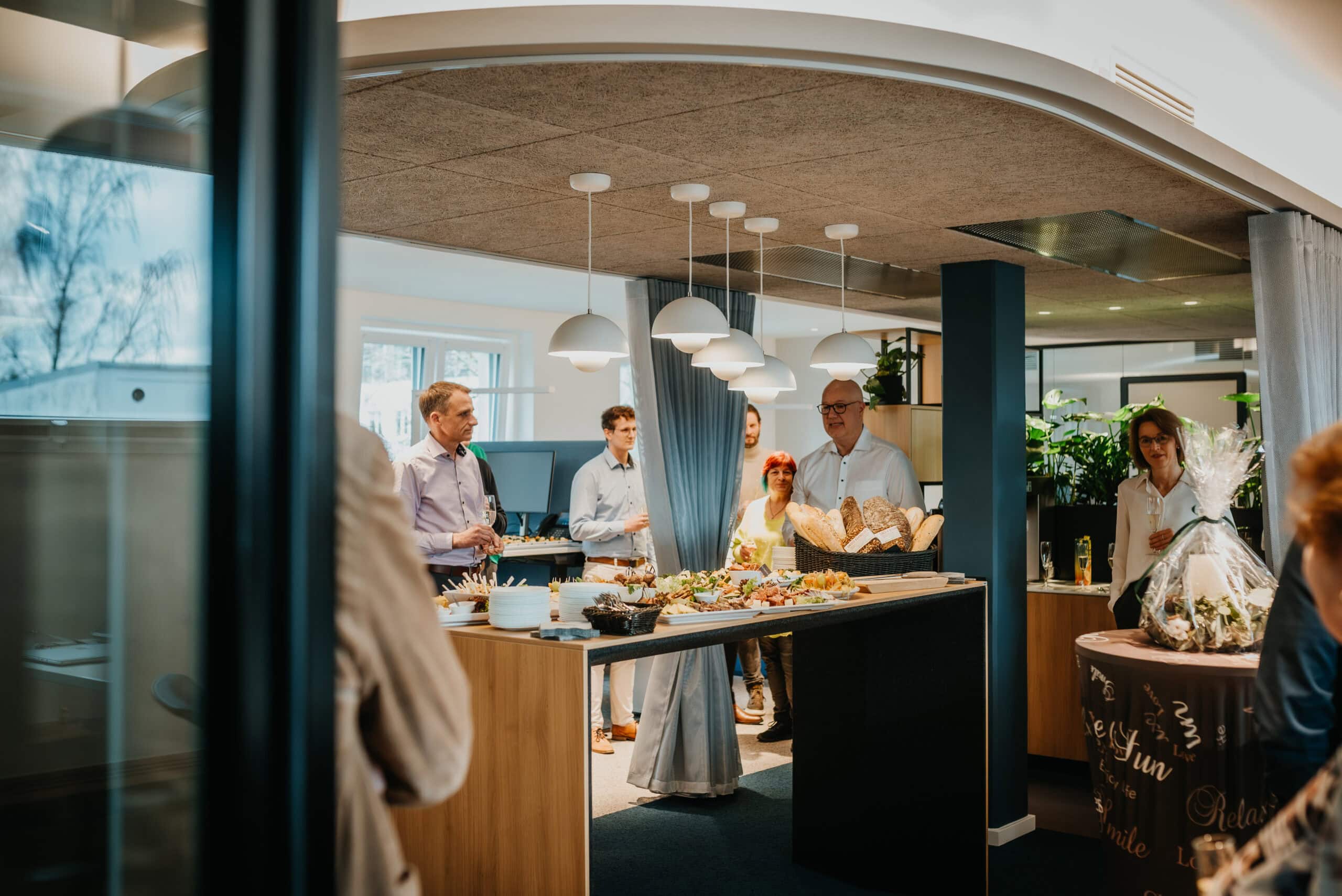 Team von Vertelln bei einem Event in einem modernen, hellen Raum mit Buffet und Gästen.