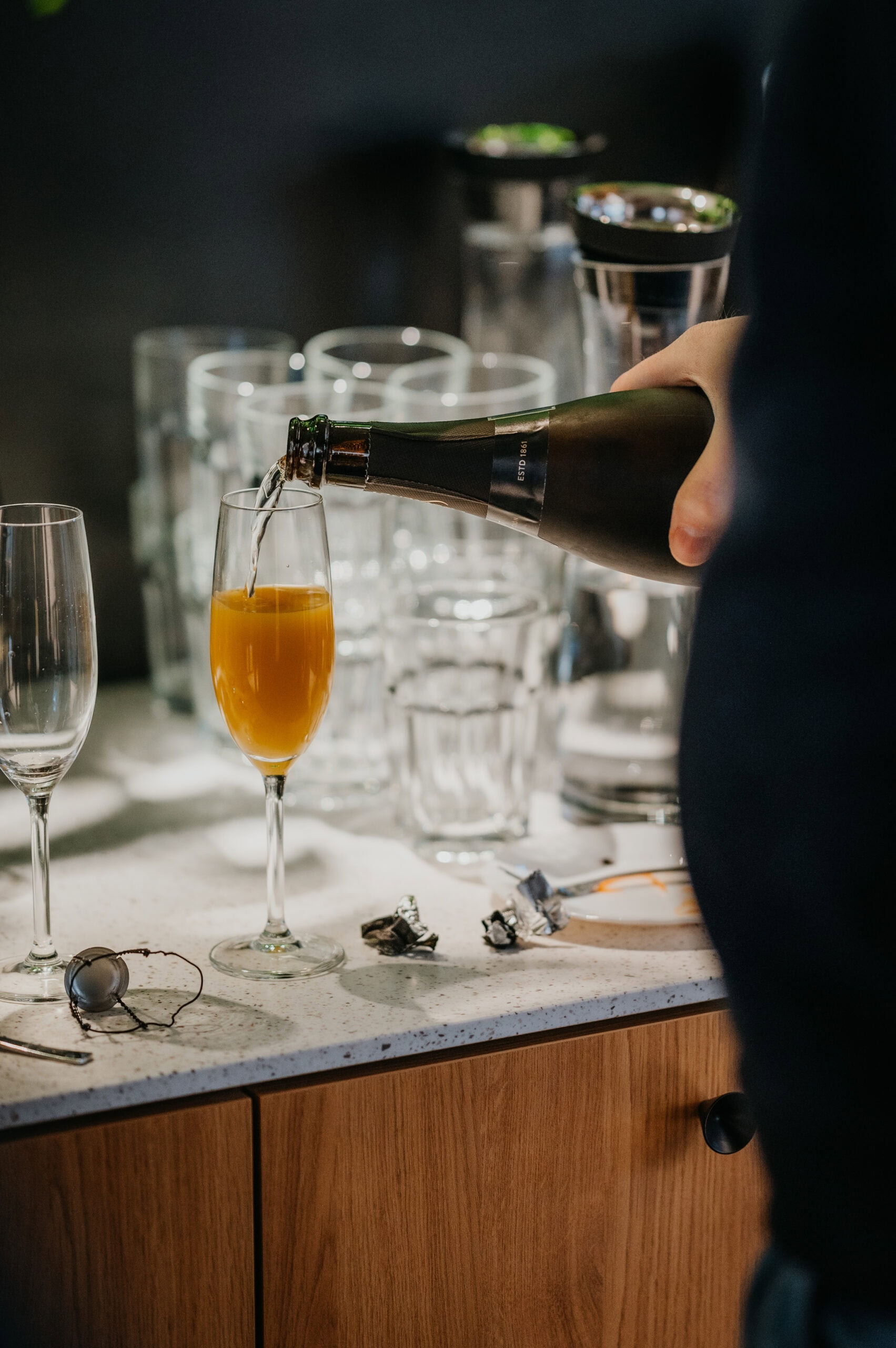 Person gießt Sekt in ein Glas bei einer Feier.