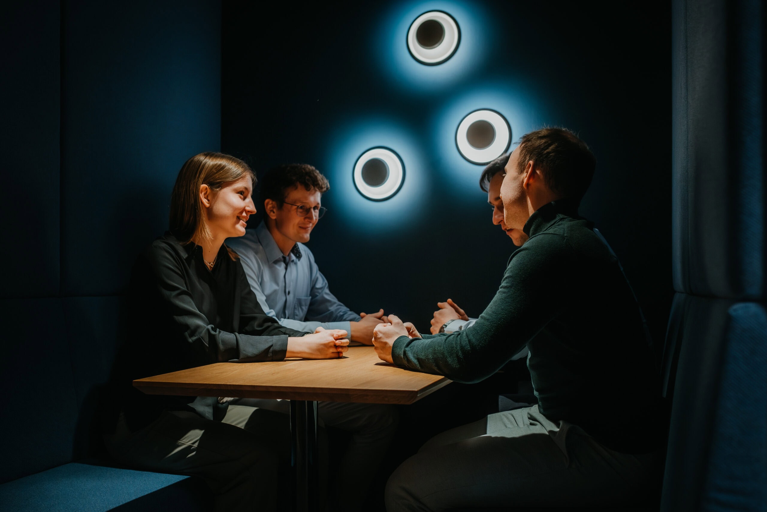 Teamarbeit in einem dunklen Raum mit moderner Beleuchtung, Fokus auf Zusammenarbeit und Innovation.