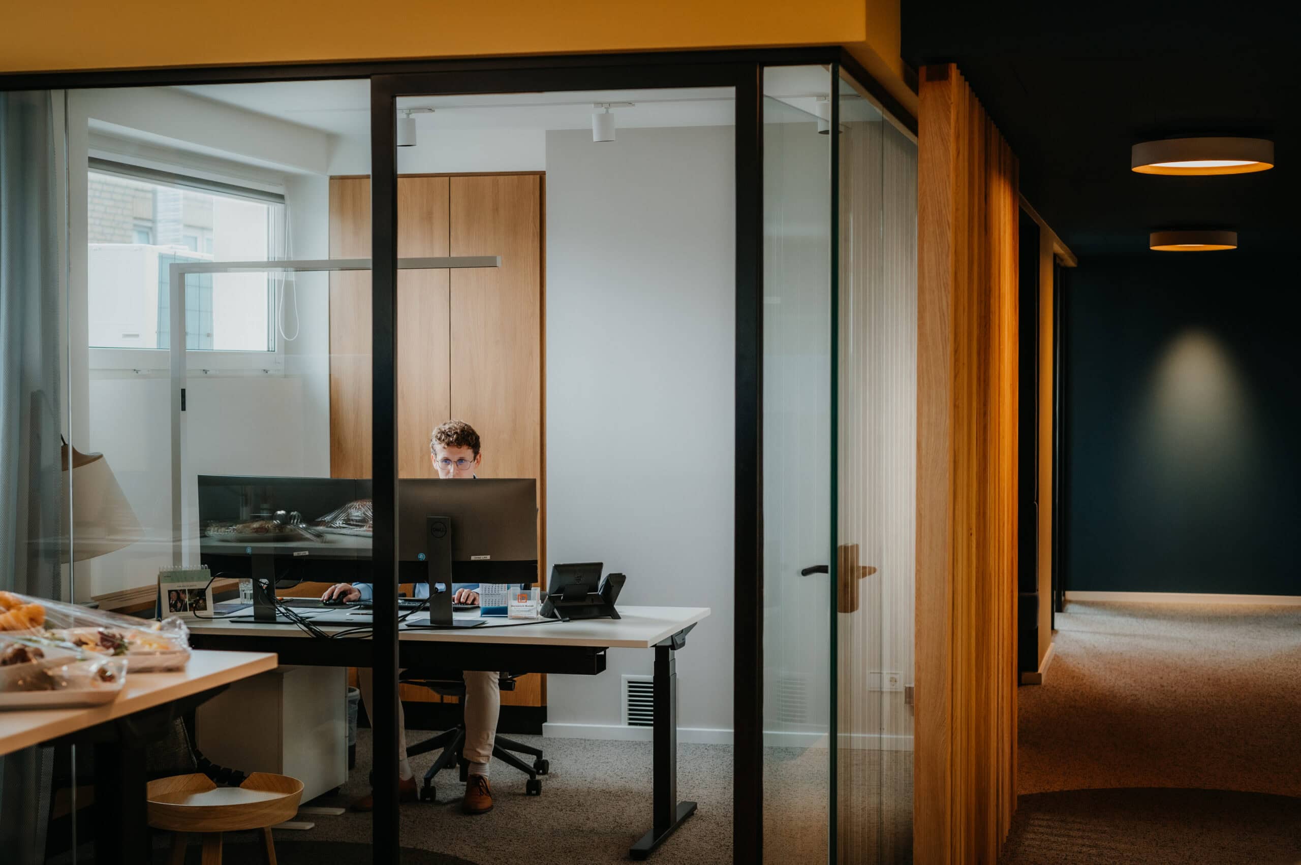 Arbeitsplatz im modernen Büro mit Glaswänden, Schreibtisch, Computer und natürlichem Licht. Perfekt.