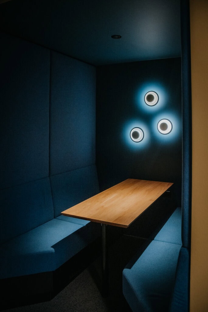 Gemütliche Ecke mit blauer Polsterung und stilvollen Wandlampen.