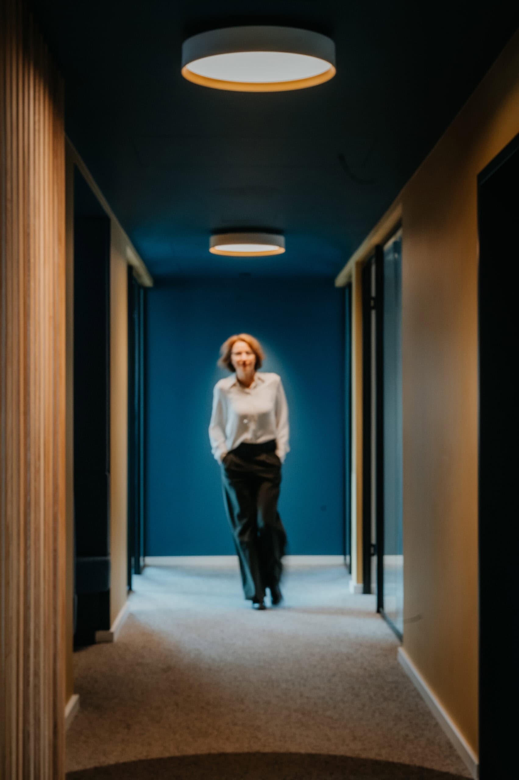 Geschäftsfrau im Flur, professionell gekleidet, im modernen Bürogebäude.