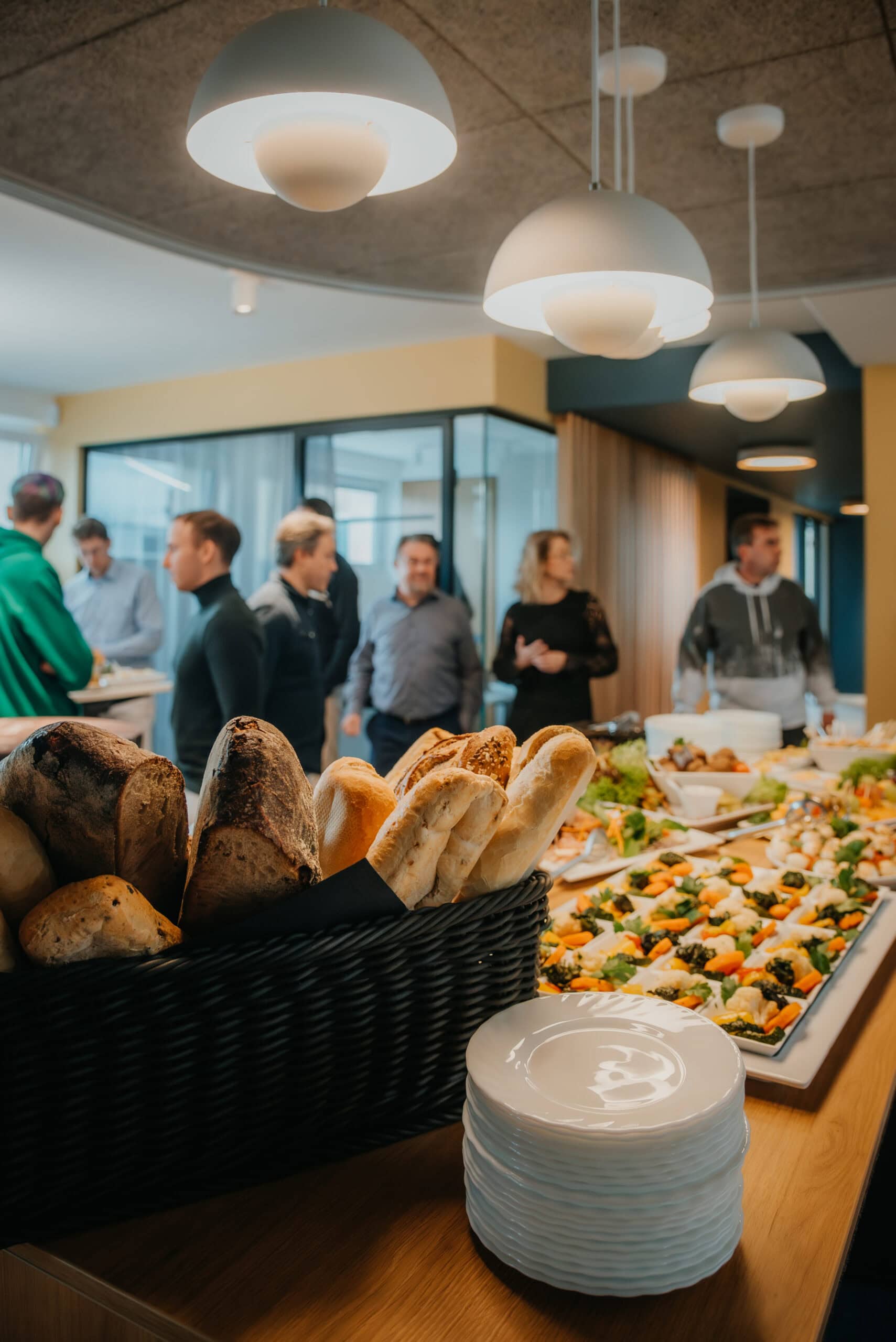 Menschen beim Kaffeetreffen mit Snacks und Buffet in modernem Raum.