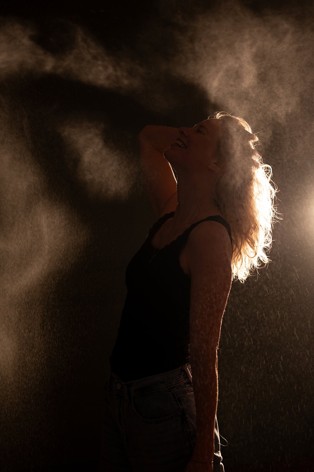 Frau im Nebel mit Lichtstrahl hinter sich, künstlerische Atmosphäre.