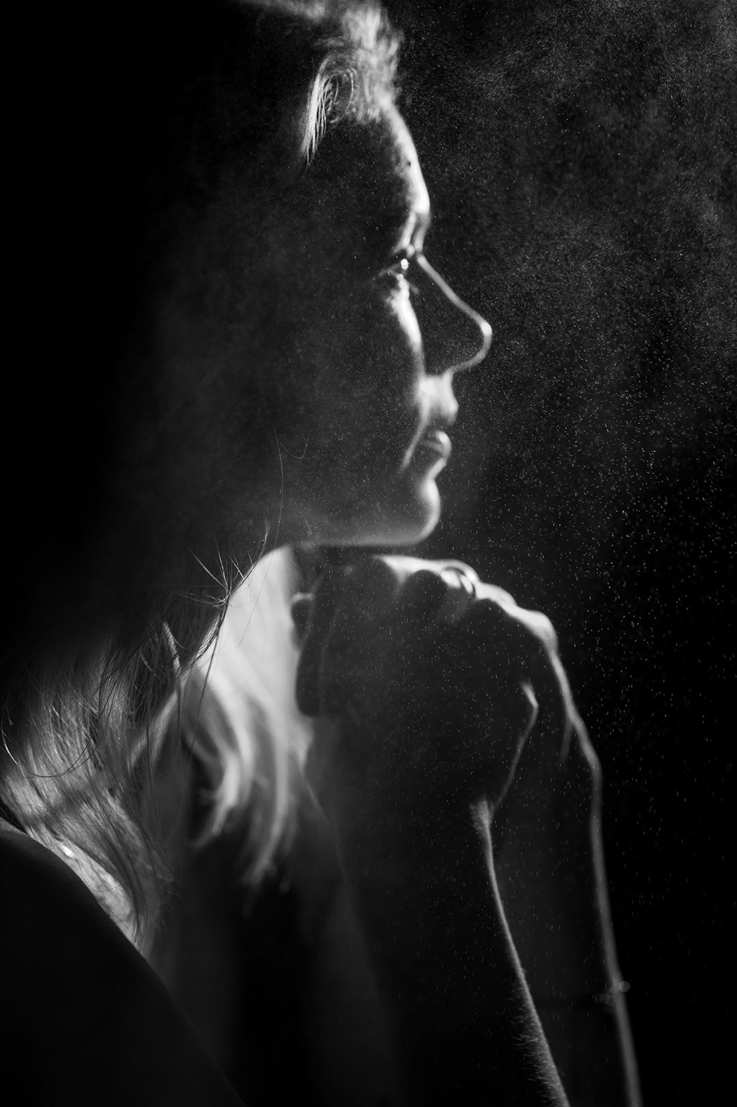 Nachdenkliche Frau in Schwarz-Weiß mit Hand an Kinn, kontemplative Stimmung.