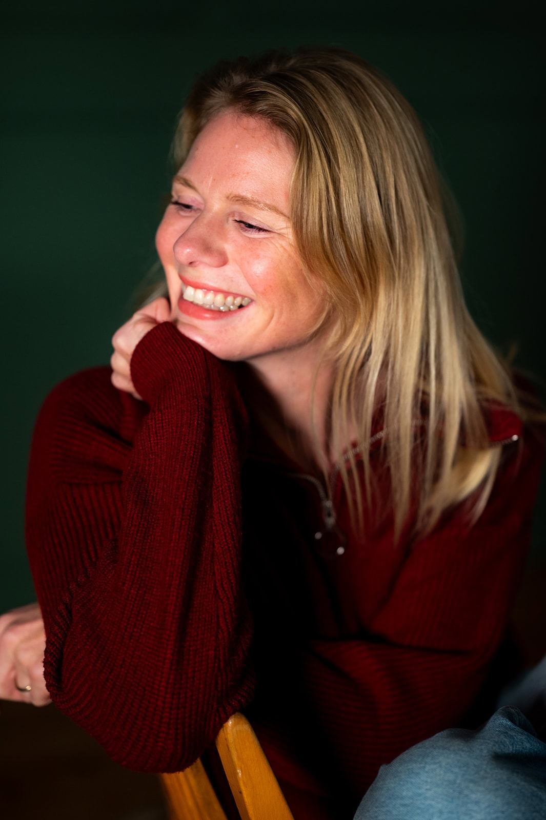 Fröhliche Frau in rotem Pullover, lächelnd und entspannt.