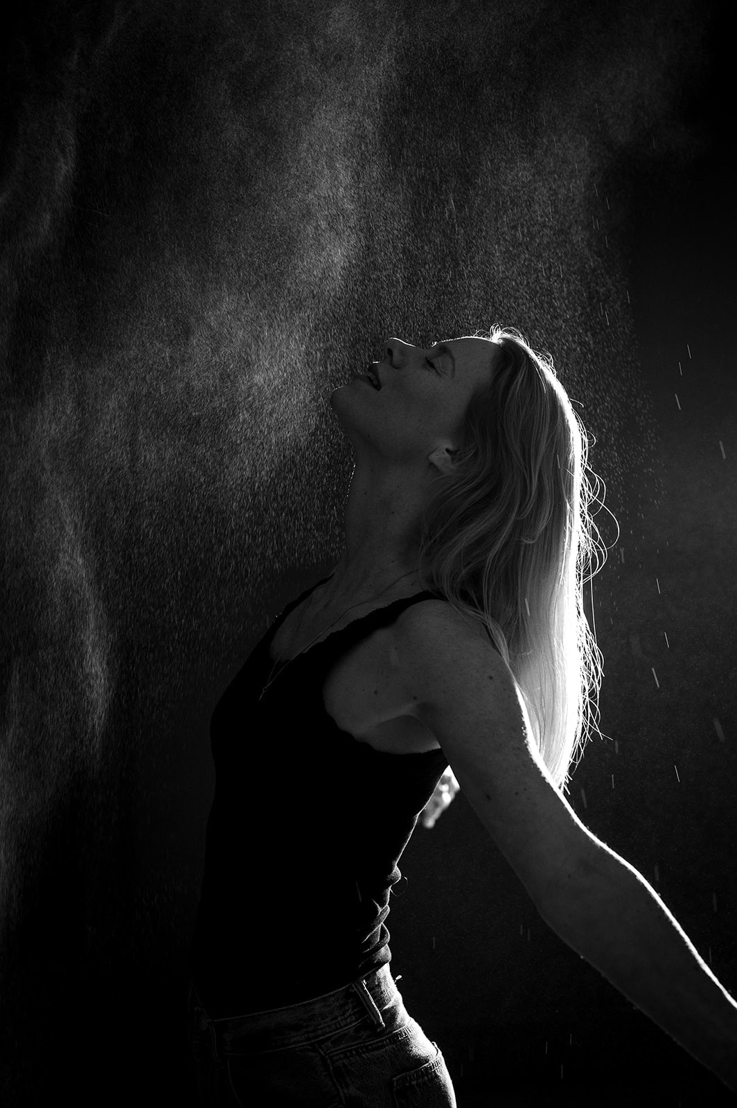 Frau beim Krafttraining, die Schweiß sprüht, in dunklem Raum.